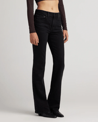 A person models Edwin’s Lark in Ramble mid-rise boot jeans, paired with a long-sleeve brown crop top and black pointed-toe shoes, against a plain light background. Only their lower torso and legs are shown.