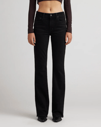 Wearing Edwin's Lark in Ramble flare leg jeans and a brown long-sleeve crop top, a person stands against a plain light background, with only their torso and legs visible.