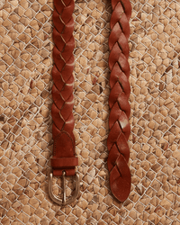 The Hartford Arthur Leather Belt in Brown, featuring genuine braided leather and a brass buckle, is displayed flat on a woven tan surface.