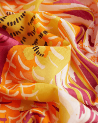 Close-up of Inoui Editions’ Square 100 Tango in Yellow, a vibrant 100% cotton fabric with swirling folds and bold yellow, orange, magenta, and black abstract patterns inspired by oversized bandana designs.