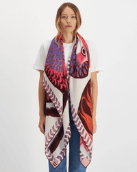 A woman with long hair wears a white T-shirt and blue jeans, styled with the Inoui Editions Square 130 Toucan in Pink, a silk cashmere scarf featuring bold abstract toucan illustrations in vibrant pink tones on a white background.