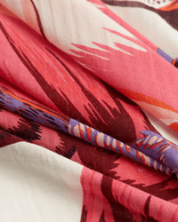 Close-up of folded fabric with a vibrant pink, red, purple, and white pattern. The Inoui Editions Square 130 Toucan in Pink is a silk cashmere scarf with abstract feather-like designs, perfect as an oversized bandana.