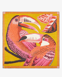 A vibrant depiction of pink and orange toucans on a yellow backdrop with colorful leaves—an ideal motif for the Inoui Editions Square 130 Toucan in Yellow silk cashmere scarf or oversized bandana.