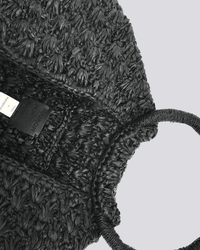 A close-up of the Clementine Bag in Black by Maison N.H Paris, featuring a textured woven finish, round handle, and visible inside tag, handmade in Madagascar and photographed from above on a light grey background.