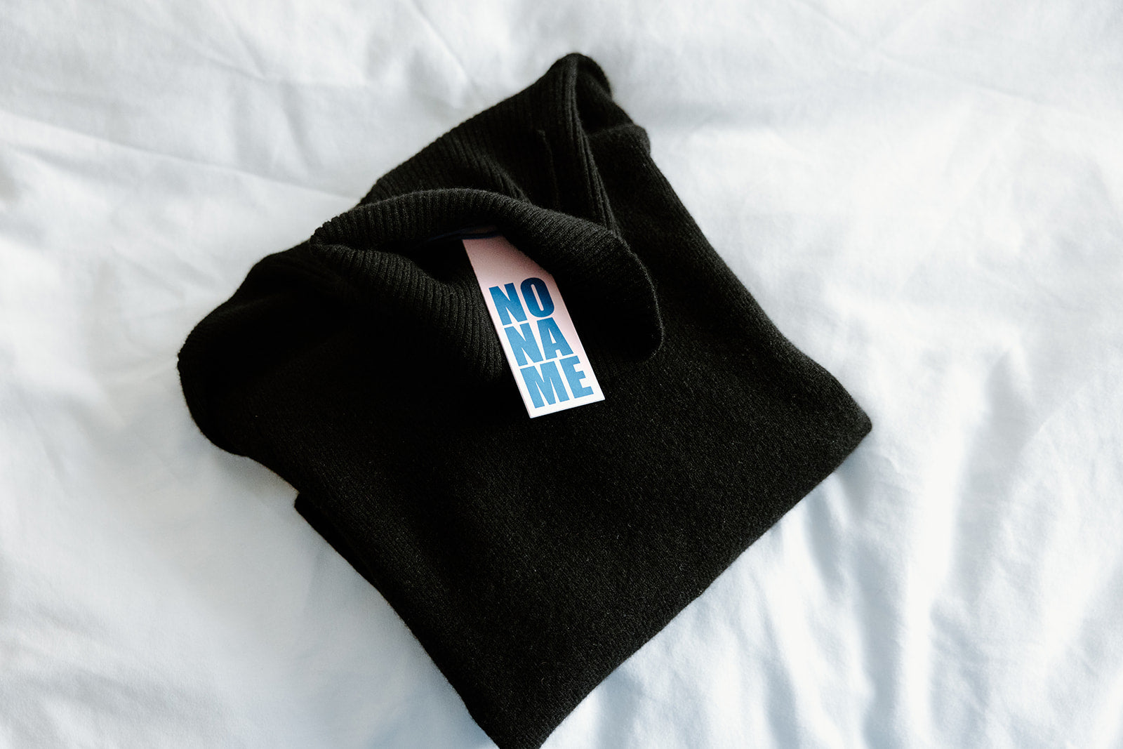 A multicolored sweater laying on a white, netted hammock.