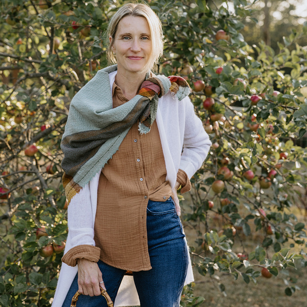 Close-up of a person wearing a light pink sweater with three buttons on the front placket.