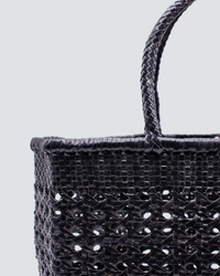 Cannage Max in Black handwoven leather basket with white accents against a gray background by Dragon Diffusion.