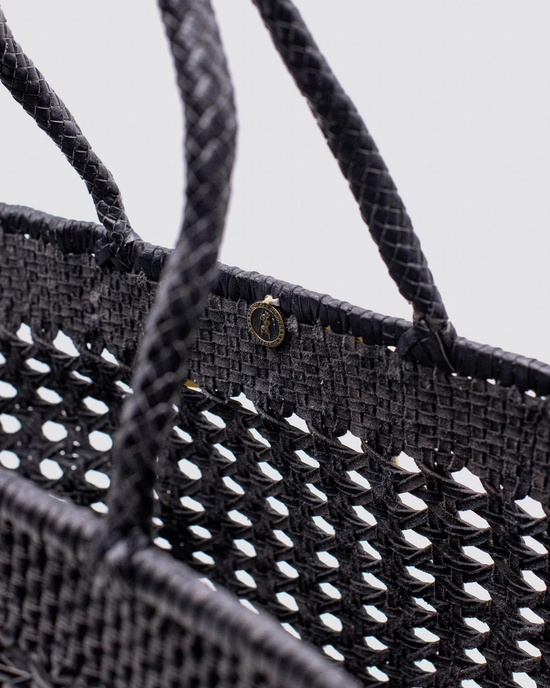 Close-up of a Dragon Diffusion Cannage Max in Black leather tote with a brand logo badge.