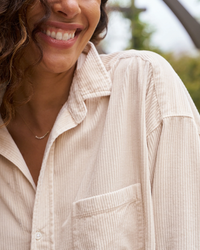 Close-up of a woman smiling, wearing the Frank & Eileen Shirley Oversized Button Up in Vintage White Cotton.