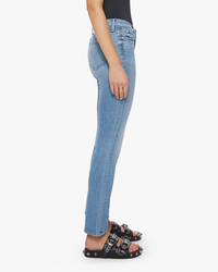 Woman standing side-on wearing Mother Denim The Rascal Skimp in Punk Charming blue jeans with an ankle-grazing inseam and black sandals.