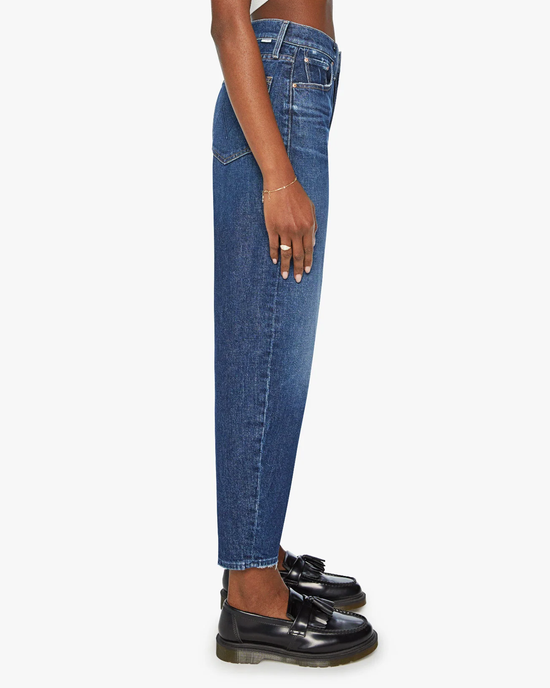 Side profile of a person wearing Mother's Yee Haw Curbside Flood high-waisted blue jeans and black loafers.