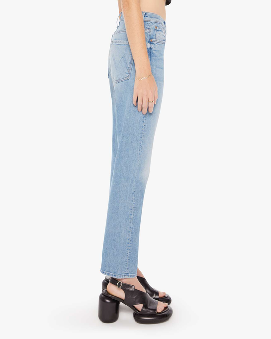 Side view of a person wearing Mother's The Ditcher Zip Flood in Love On The Beat blue jeans with an ankle length jean design and black platform sandals against a white background.