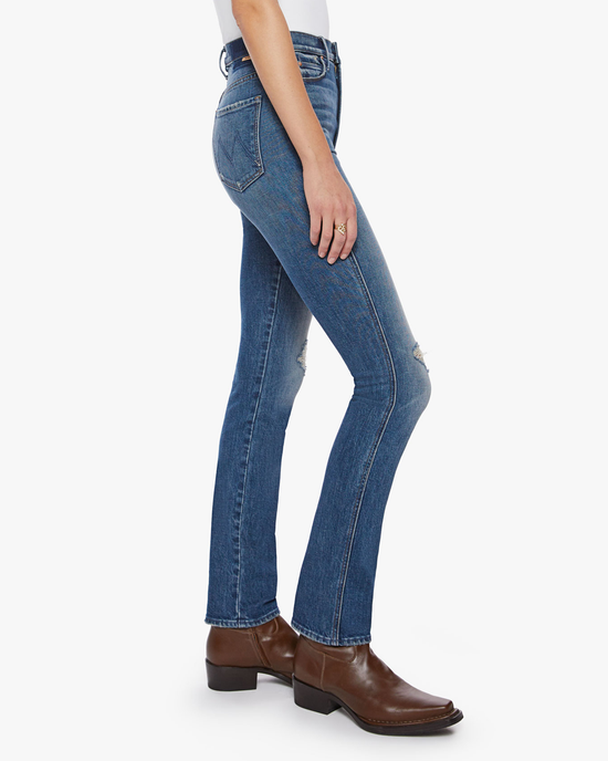 Woman wearing Mother high waisted denim and brown boots standing sideways.