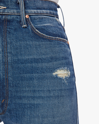 Close-up of Mother's High Waisted Dazzler Double Heel in Morning Chores denim jeans with a small distressed area on the thigh.
