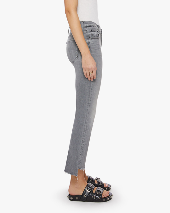 Side view of a person wearing Mother's The Insider Crop Step Fray in Barely There gray jeans and black sandals.