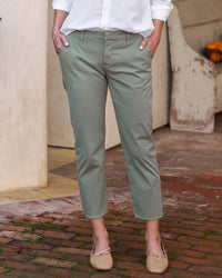 Person standing in an outdoor setting wearing Frank & Eileen's Wicklow Italian Chino in Rosemary and beige espadrilles, hands partially tucked in pant pockets.