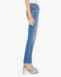 Side view of a person wearing blue Mother Denim The Rascal Ankle Fray in Opposites Attract jeans and white high-heeled sandals.