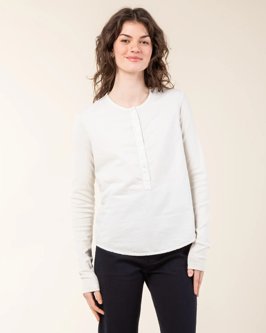 Woman in a white long-sleeve Apt Henley in Oyster made of organic cotton and black pants standing against a neutral background by Prairie Underground.