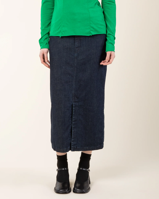 Person wearing a green top, Spring St. Skirt in Mechanic made from organic cotton denim, black socks, and black ankle boots.