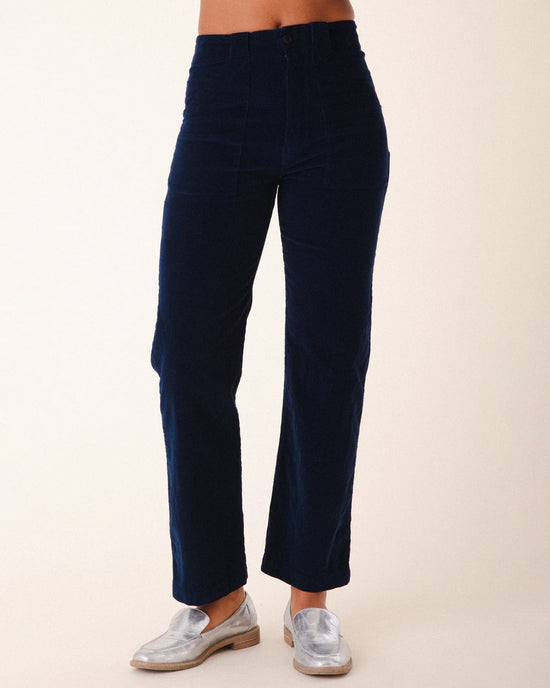 A person wears Prairie Underground's Corduroy Carpenter Pant in Midnight—high-rise, straight-leg, navy blue corduroy—paired with shiny silver loafers, shown waist to feet against a plain light background.
