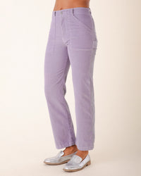A person wearing Prairie Underground’s Corduroy Carpenter Pant in Silver Mist, featuring a high-waisted, straight-leg fit with front patch pockets, paired with silver metallic loafers, stands against a plain light background.
