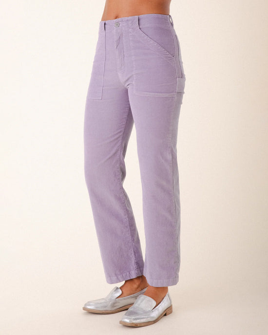 A person wearing Prairie Underground’s Corduroy Carpenter Pant in Silver Mist, featuring a high-waisted, straight-leg fit with front patch pockets, paired with silver metallic loafers, stands against a plain light background.