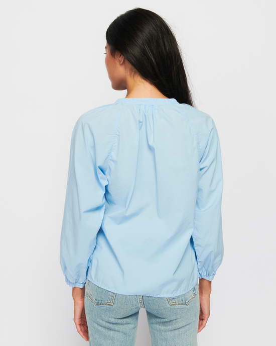 Woman standing with her back to the camera, wearing the Nation LTD Desire Dolman Button Up in Shirting and denim jeans.