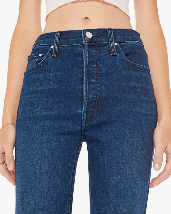 Close-up of a woman wearing Mother Denim The Tripper Ankle in Taking Shape blue jeans showing the front waistband and pockets of her high-rise flare jeans.