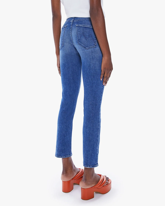 Woman wearing The Mid Rise Dazzler Ankle in Wish On A Star denim jeans by Mother and orange sandals, viewed from behind.