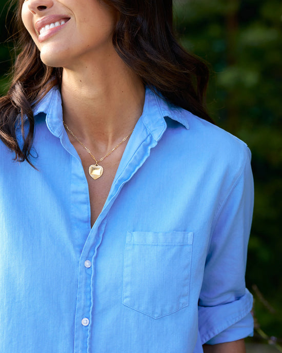 Close-up of a smiling woman wearing a Frank & Eileen Mary Classic Shirtdress in Tide and a heart-shaped pendant necklace.