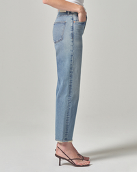 Side view of a person wearing Citizens of Humanity Florence Wide Straight in Fontana jeans with a vintage fit and strappy sandals standing against a neutral background.