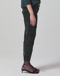Person wearing Citizens of Humanity Agni Utility Trouser in Seaweed Cord and one black sandal standing against a neutral background.