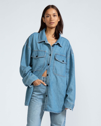 A woman wearing an ASKK NY Denim Shirt Jacket in Jackson and jeans against a plain background.