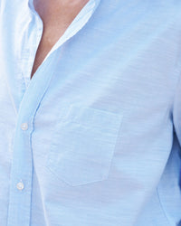 Close-up of a Frank & Eileen Eileen Relaxed Button-Up Shirt in Blue Casual Cotton with a visible pocket and partial view of a person's chest, focusing on the fabric texture and buttons.