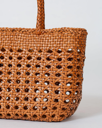 Close-up of a Dragon Diffusion handwoven brown basket in the Cannage Kanpur Big in Tan design.