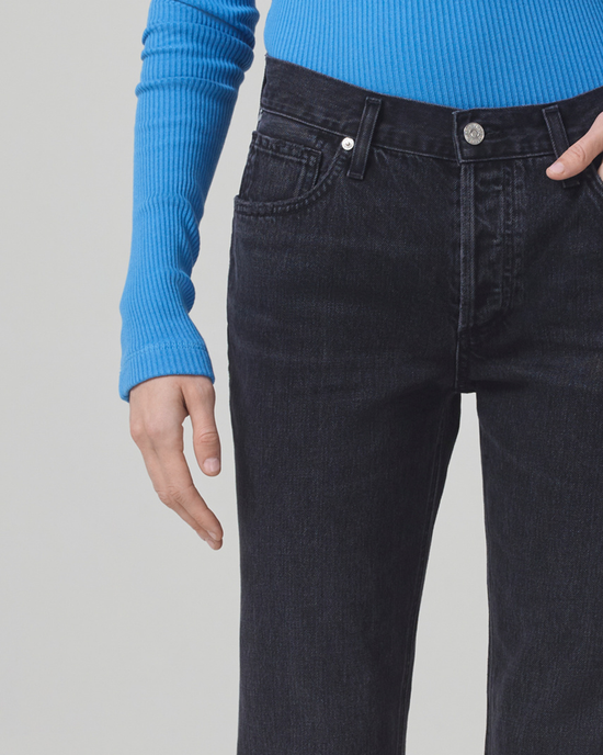 Close-up of a person wearing a blue sweater and Citizens of Humanity Neve Low Slung Relaxed in Voila pants made from organic cotton, with one hand partially in their pocket.