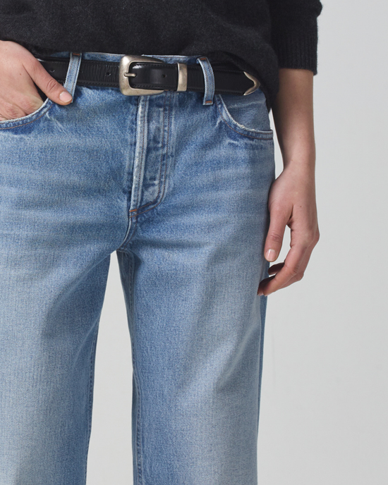 A person adjusting a Neve Low Slung Relaxed belt on a pair of Misty blue jeans made from organic cotton by Citizens of Humanity.