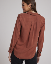 Woman photographed from behind wearing a rust-colored Bella Dahl Two Pocket Classic Button Down in Autumn Amber with a yoke design and front button closure.