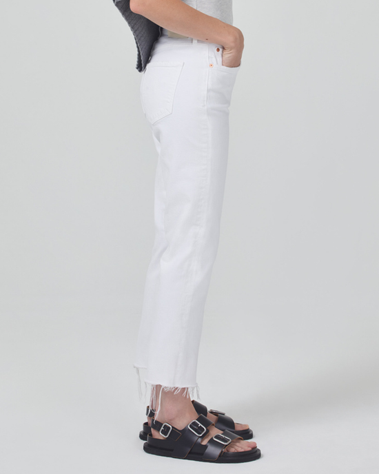 Side view of a person wearing white frayed mid rise jeans and black sandals standing against a plain background, featuring the Citizens of Humanity Isola Cropped Boot in Mayfair.