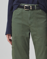 Close-up view of a person wearing green non-stretch twill pants with a black belt and a navy blue top made from organic cotton by Citizens of Humanity Marcelle Low Slung Cargo in Surplus Sateen.