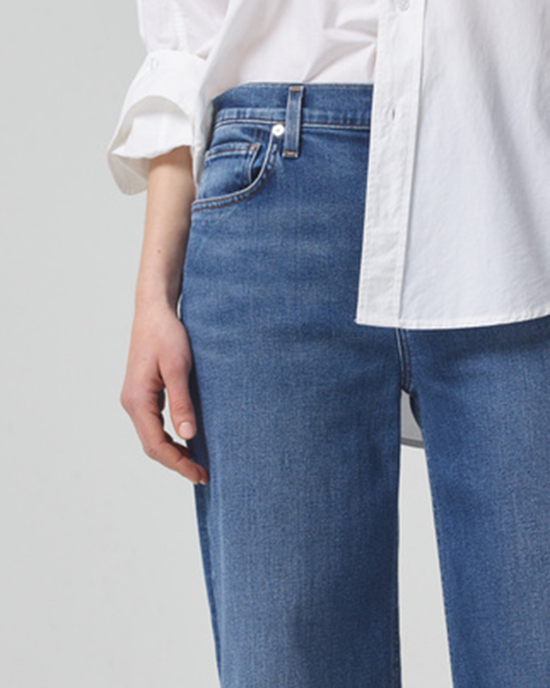 Close-up of a person wearing a white shirt and Loli Mid Rise Baggy in Palazzo jeans by Citizens of Humanity.