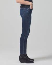 Side view of a person wearing Citizens of Humanity Sloane Skinny w/ Clean Hem in Baltic jeans and black boots.
