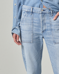 Close-up of a person wearing light blue Citizens of Humanity Leah Cargo jeans in Pinpoint and a matching jacket, focusing on the waist area with a hand resting lightly on the hip.