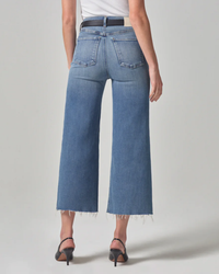 Woman wearing Lyra Crop Wide Leg in Abliss denim jeans by Citizens of Humanity with frayed hems and black heels.