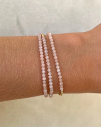 A person's wrist adorned with two 2MM Sig Bracelets with Nude Moonstone & Yellow Gold from Karen Lazar Design.