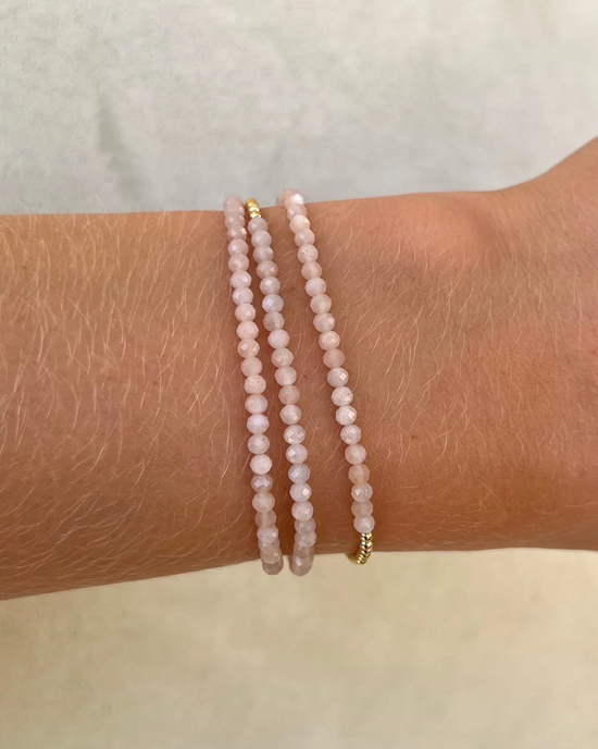 A person's wrist adorned with two 2MM Sig Bracelets with Nude Moonstone & Yellow Gold from Karen Lazar Design.