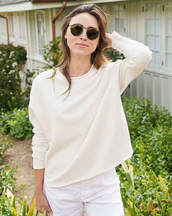 Woman in a Frank & Eileen Anna Long Sleeve Capelet in Vintage White and sunglasses standing outdoors.