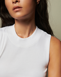 Close-up of a woman in a Joan Sleeveless Mock Neck in white from Nation LTD.