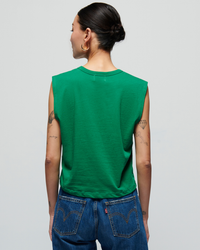 Woman in a Nation LTD Collins Crewneck Solid Tank in Verdant Green and high-rise denim jeans viewed from the back, showcasing tattoos on her arms.