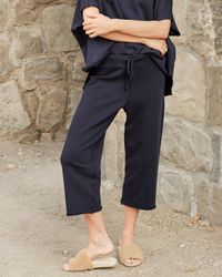 Woman in casual navy blue Frank & Eileen Catherine Sweatpant in British Royal Navy apparel standing by a stone wall.